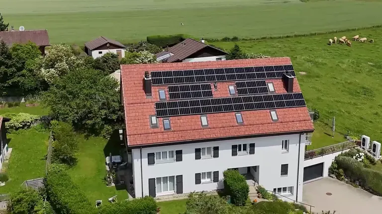 Maison romande dont tout le pan de toit est couvert de panneaux solaires, vue aérienne